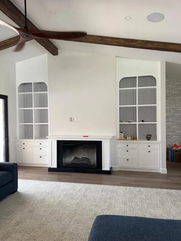 White built-ins with arched glass cabinets flanking a fireplace