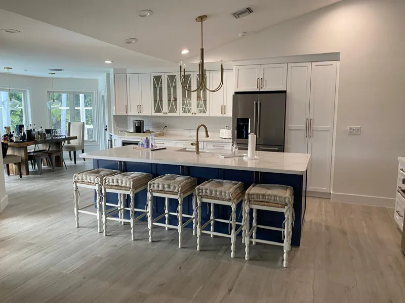 Open kitchen with white perimeter cabinets and a navy island seating five