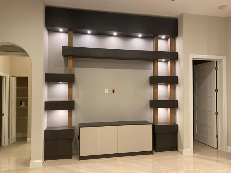 Media wall with lit walnut shelving and a low lacquered cabinet